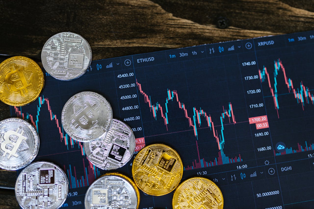 Close-up of gold and silver cryptocurrency coins on a digital trading chart.